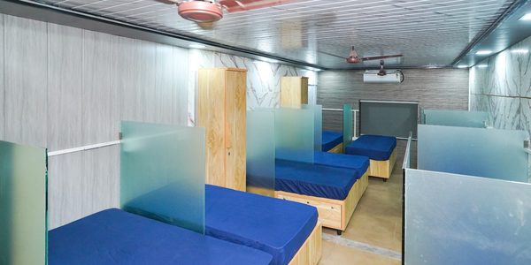 Semi-private bed bay divided by frosted glass panels, with wardrobe and wall-mounted air conditioning, at Zest Stays 1054