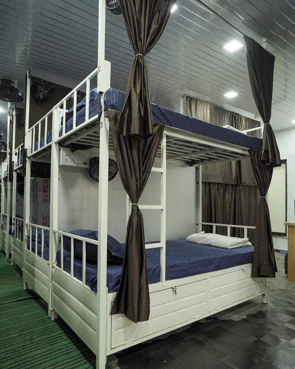 Air-conditioned dormitory at Zest Stays 1054 — bunk beds with privacy curtains, personal fans and lockable storage